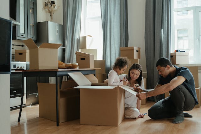 Family in a kitchen filled with moving boxes, joyfully drawing and playing with their child, symbolizing a new beginning with Movers Plus's moving services in Frisco.